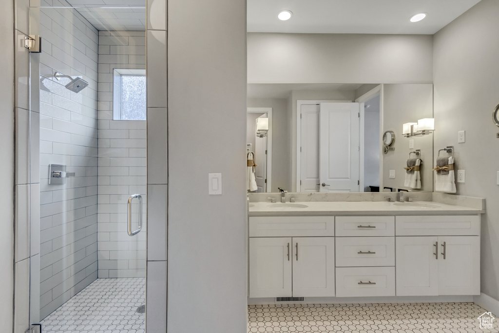 Bathroom featuring tile flooring, double sink vanity, and a shower with shower door