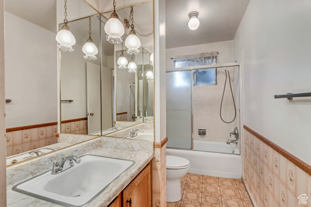 Full bathroom with enclosed tub / shower combo, vanity, toilet, and tile floors