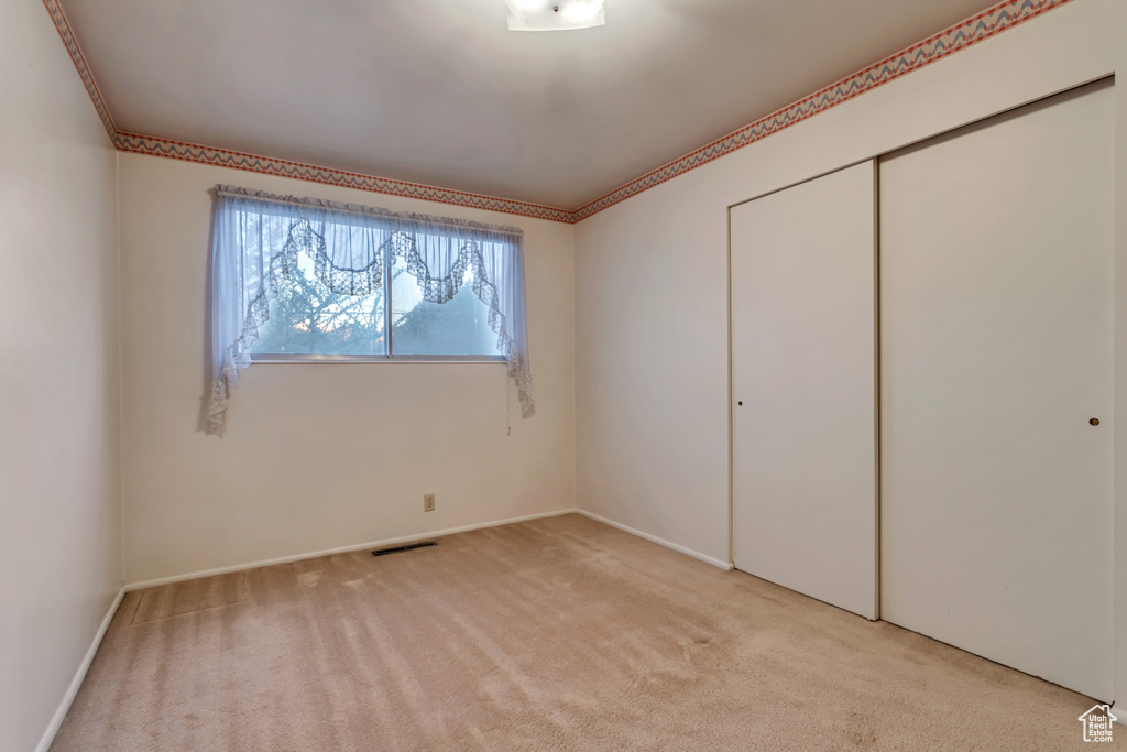 Unfurnished bedroom featuring light colored carpet, a closet, and ornamental molding