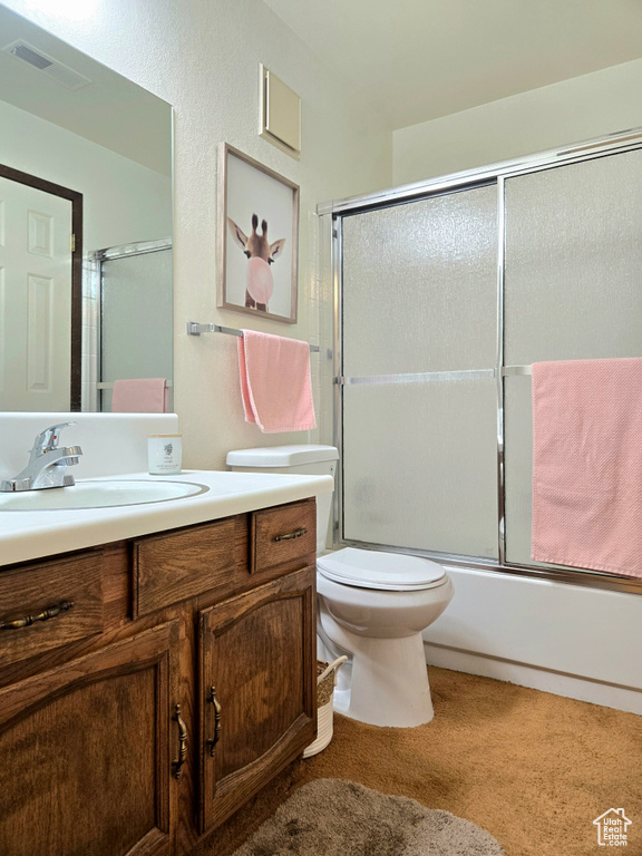 Full bathroom with vanity, toilet, and bath / shower combo with glass door