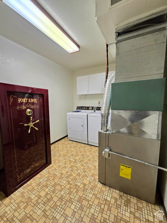 Clothes washing area with light tile flooring, cabinets, and washing machine and clothes dryer