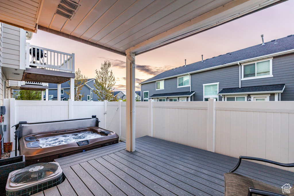 Deck at dusk featuring a covered hot tub