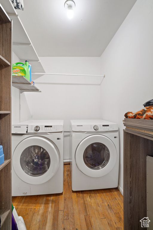 Laundry area with light hardwood / wood-style flooring and washing machine and clothes dryer