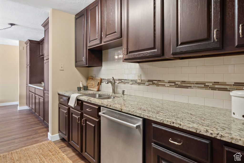 Kitchen with light stone countertops, dishwasher, tasteful backsplash, sink, and light wood-type flooring