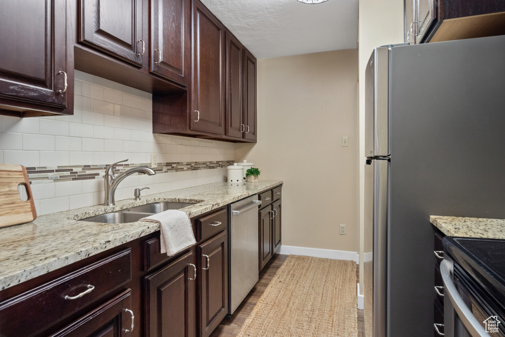 Kitchen featuring backsplash, sink, dark brown cabinets, and stainless steel dishwasher