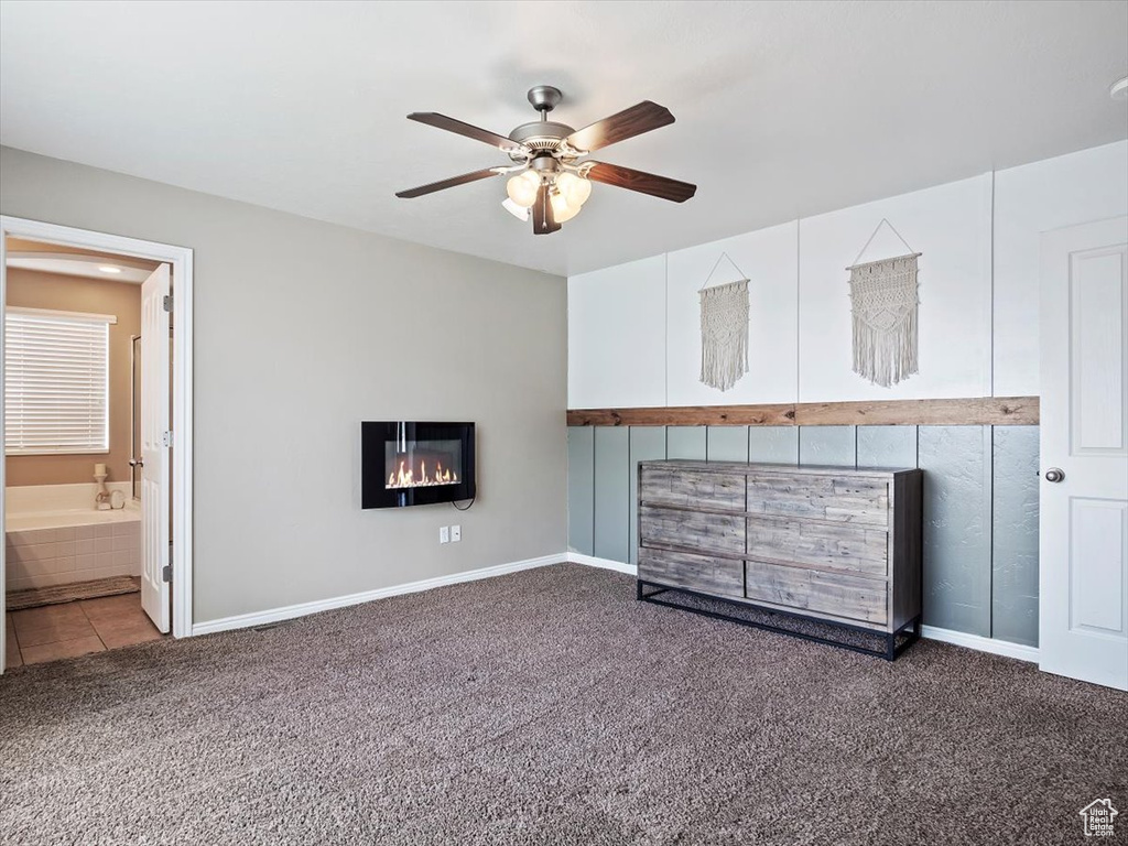 Unfurnished living room with ceiling fan and dark carpet