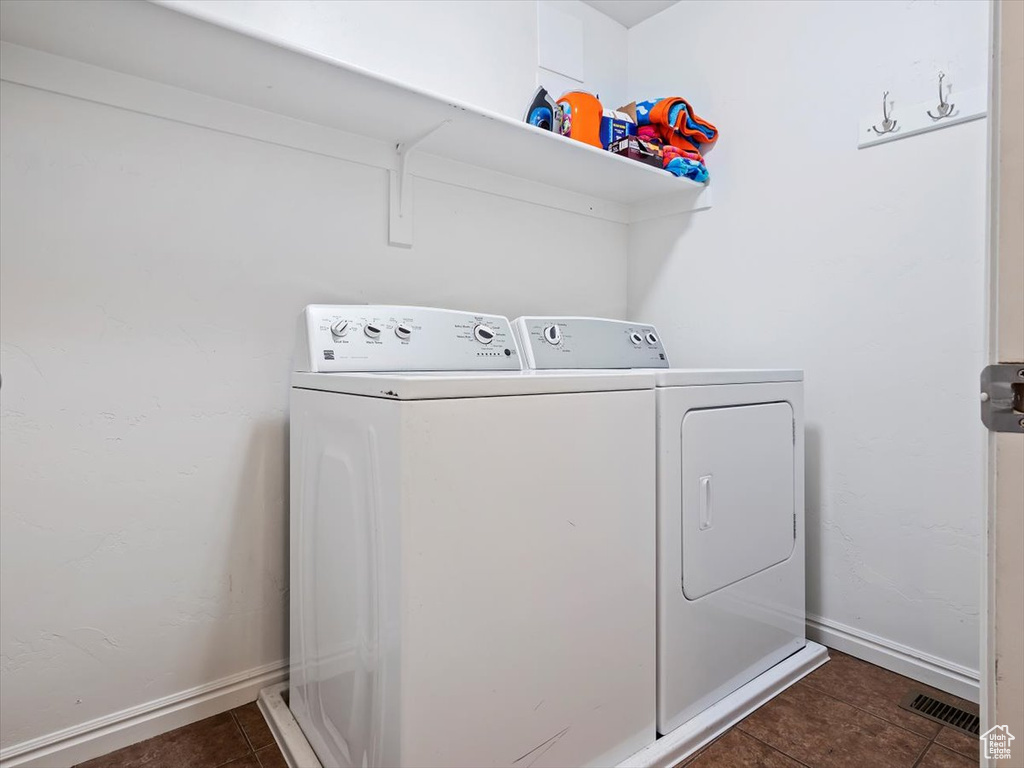 Laundry area with dark tile flooring and independent washer and dryer