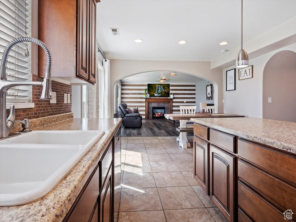 Kitchen with sink, light hardwood / wood-style flooring, hanging light fixtures, and backsplash