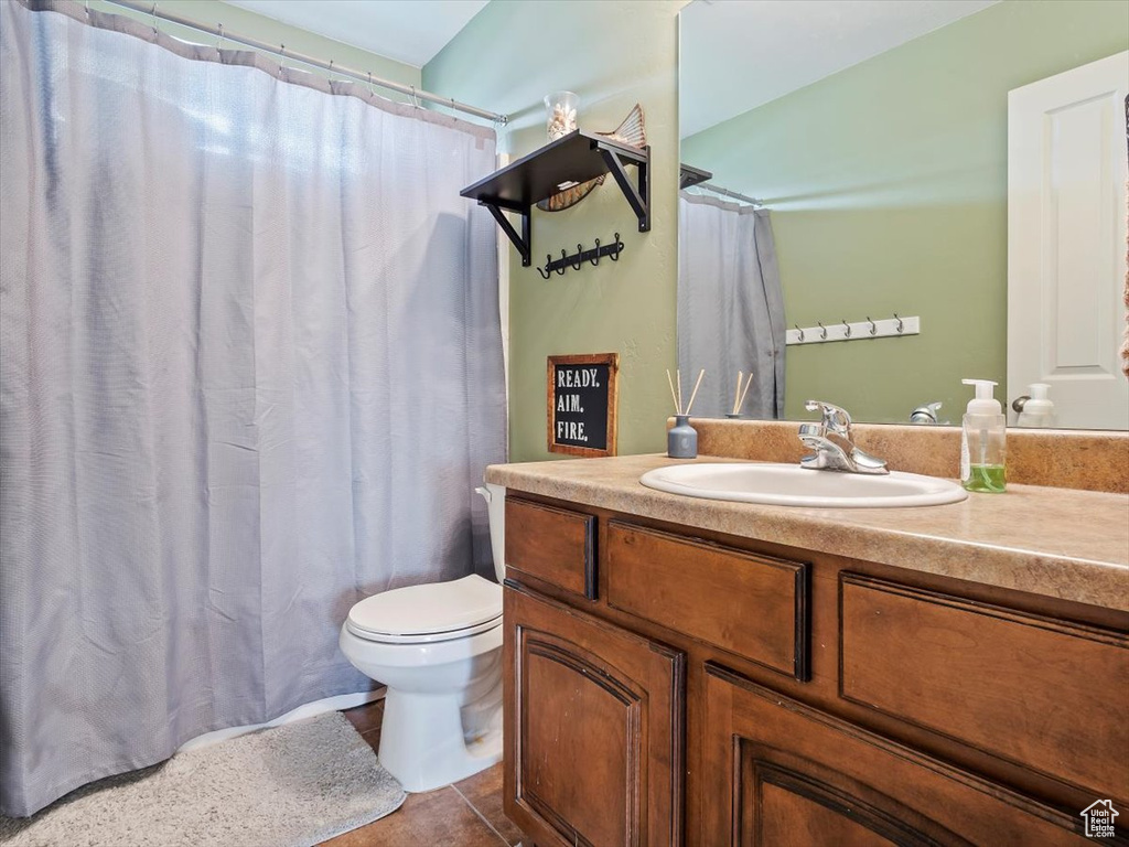 Bathroom with tile flooring, vanity with extensive cabinet space, and toilet