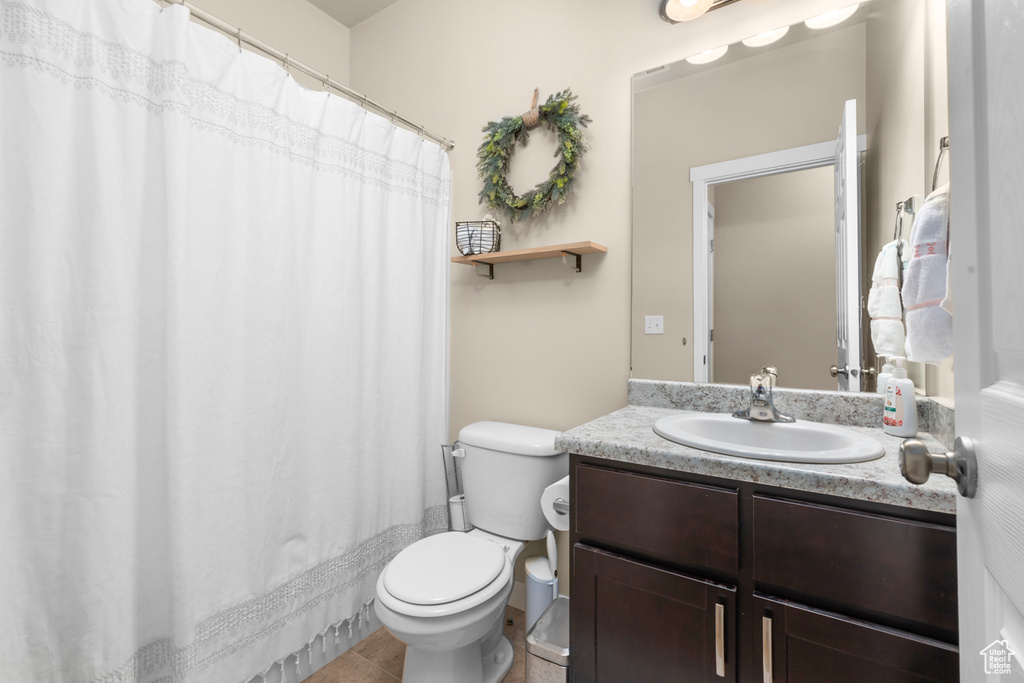 Bathroom featuring oversized vanity, toilet, and tile flooring