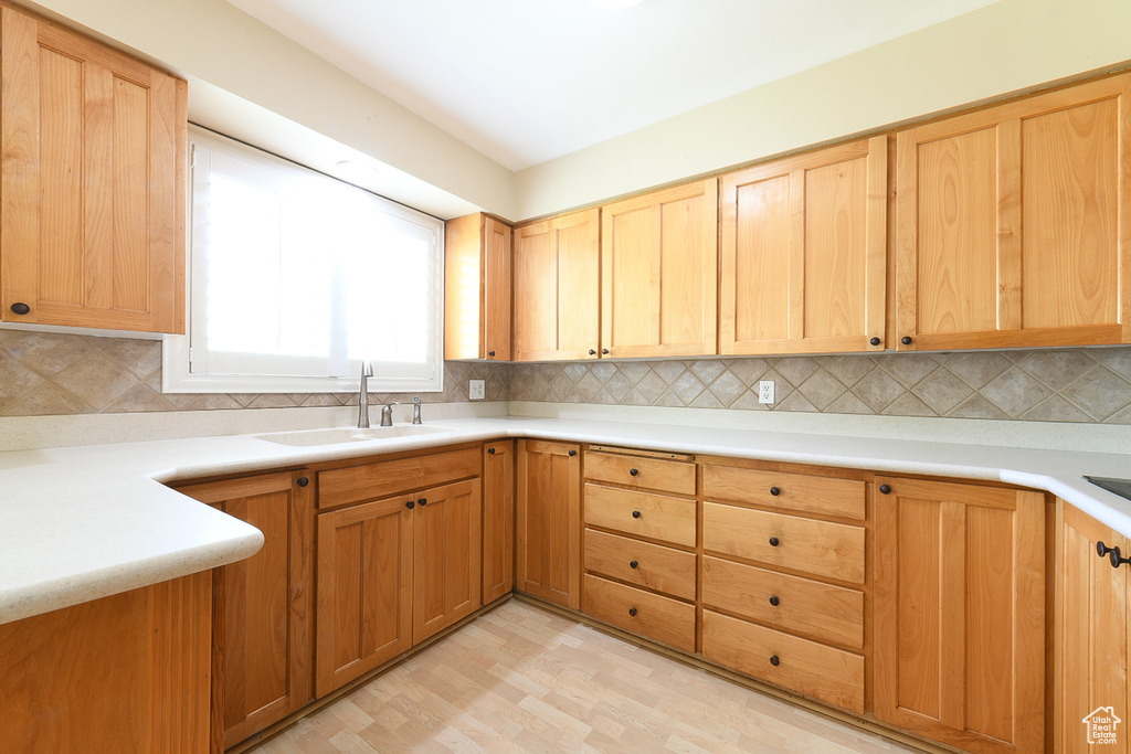 Kitchen featuring tasteful backsplash, light hardwood / wood-style floors, and sink