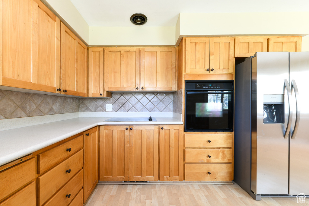 Kitchen featuring light hardwood / wood-style floors, backsplash, and black appliances