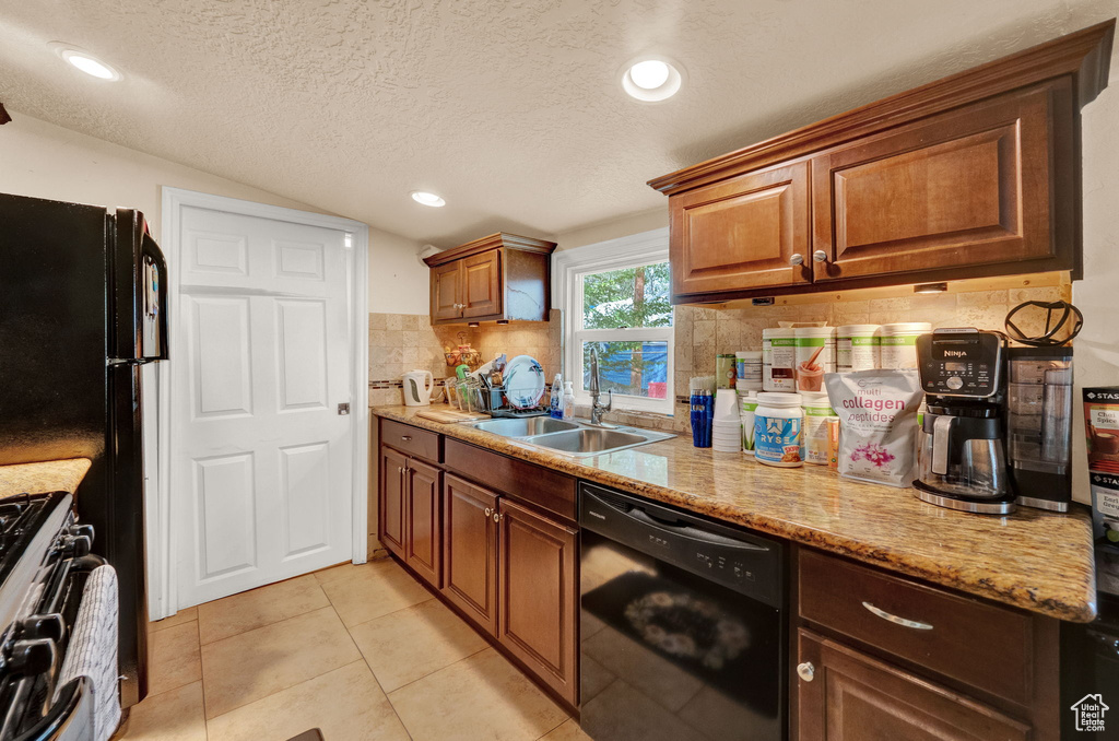 Kitchen featuring a textured ceiling, range, sink, dishwasher, and tasteful backsplash