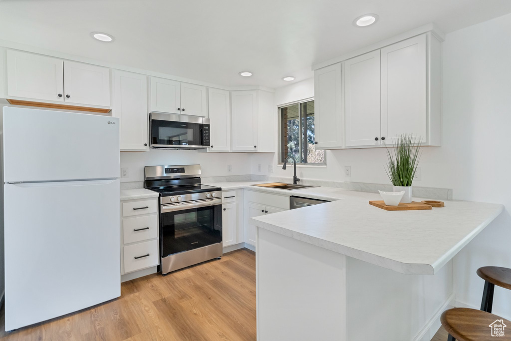 Kitchen featuring kitchen peninsula, a kitchen bar, light hardwood / wood-style flooring, stainless steel appliances, and sink