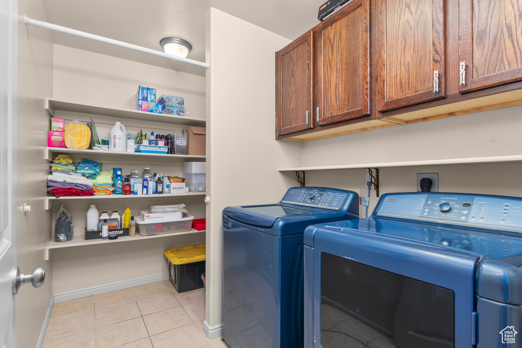 Laundry area featuring hookup for an electric dryer, light tile flooring, cabinets, and washer and clothes dryer