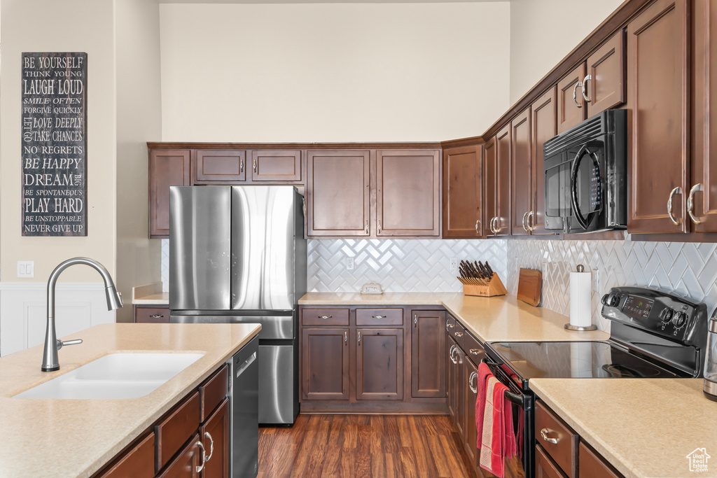 Kitchen with dark brown cabinetry, sink, tasteful backsplash, dark hardwood / wood-style flooring, and black appliances