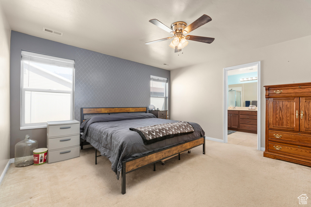 Bedroom with ceiling fan, light carpet, and ensuite bathroom