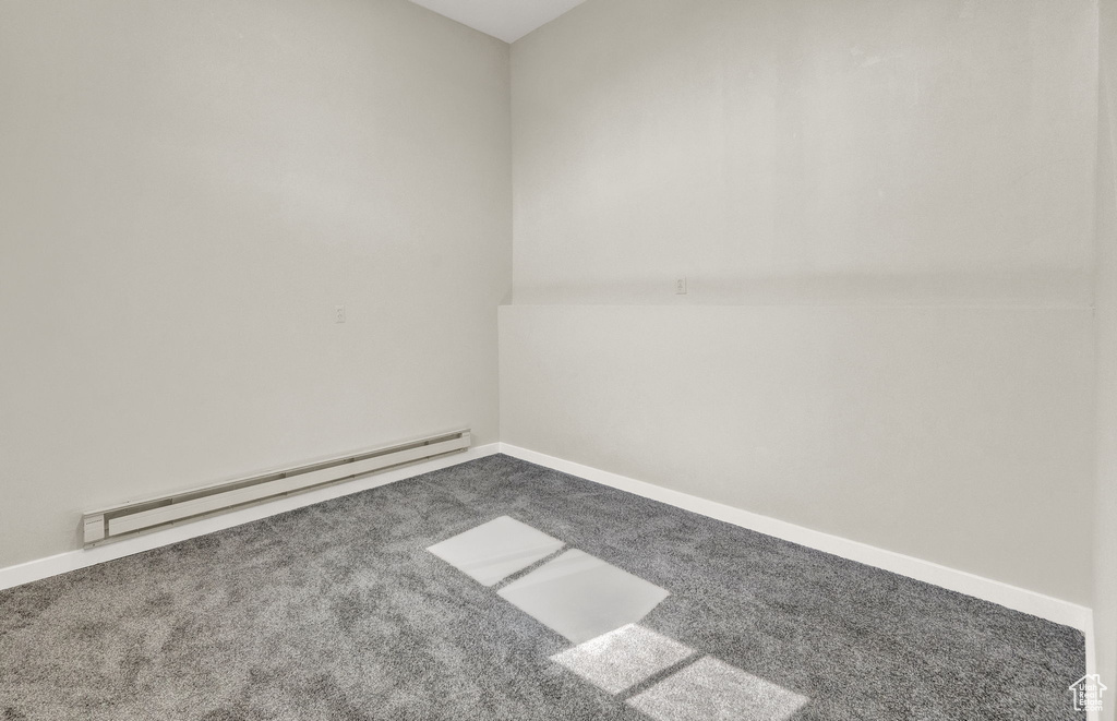 Carpeted empty room with a baseboard heating unit