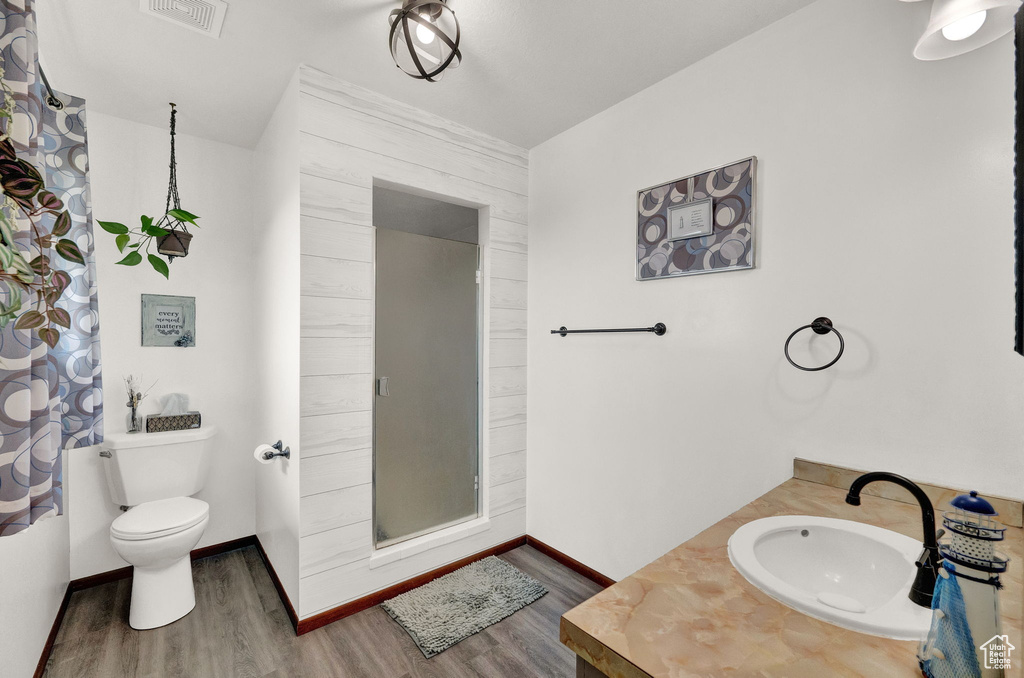 Bathroom featuring a shower with curtain, wood-type flooring, vanity, and toilet