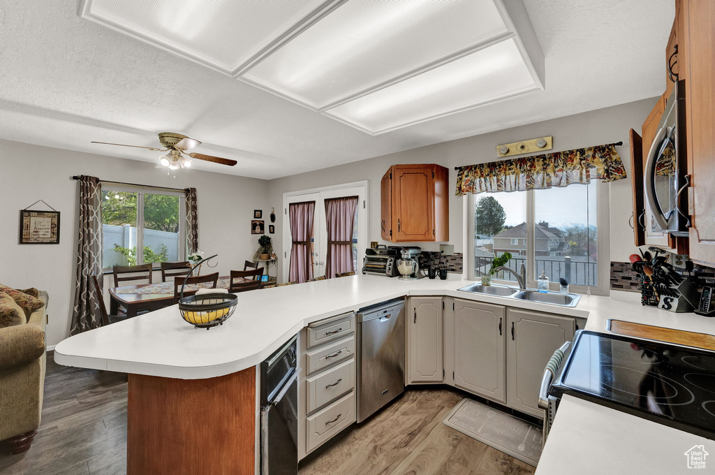 Kitchen with sink, kitchen peninsula, light wood-type flooring, and stainless steel appliances
