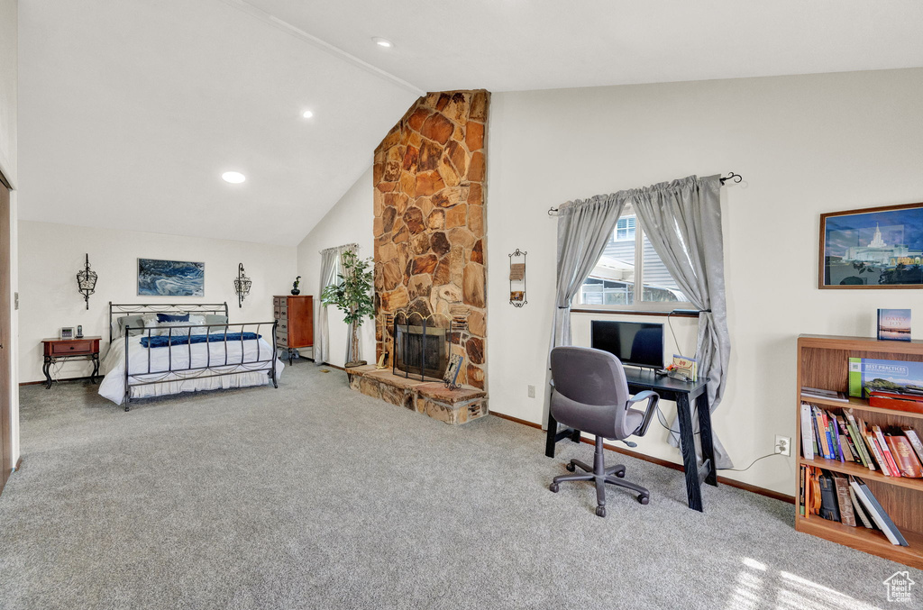 Carpeted bedroom featuring lofted ceiling and a stone fireplace