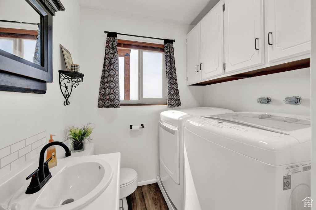 Laundry room with sink, independent washer and dryer, a wealth of natural light, and dark wood-type flooring