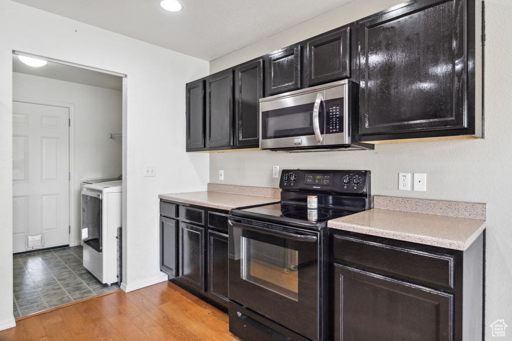 Kitchen featuring black / electric stove, light tile floors, and washer / clothes dryer