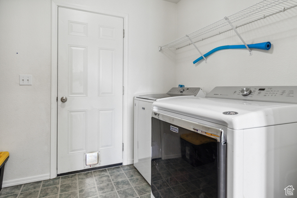 Washroom featuring dark tile floors and separate washer and dryer