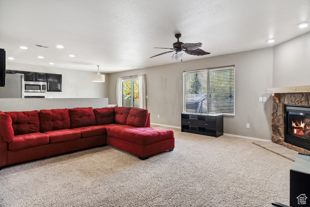 Living room with a fireplace, ceiling fan, and light carpet