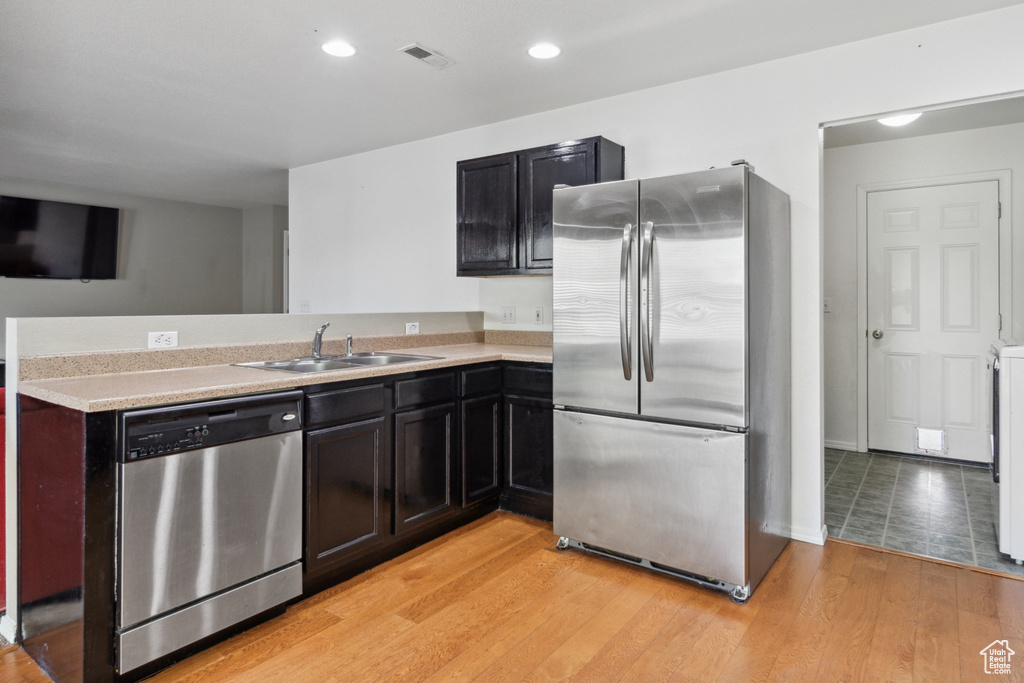 Kitchen featuring kitchen peninsula, light hardwood / wood-style flooring, stainless steel appliances, and sink