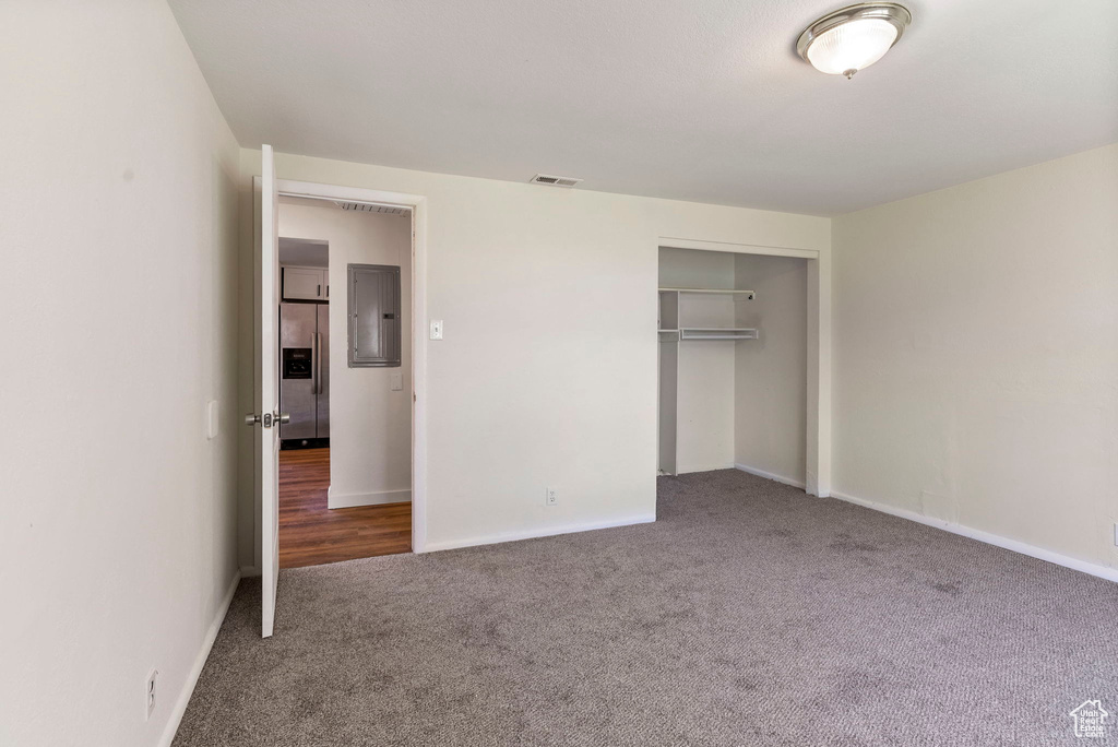 Unfurnished bedroom featuring a closet, stainless steel fridge with ice dispenser, and carpet flooring