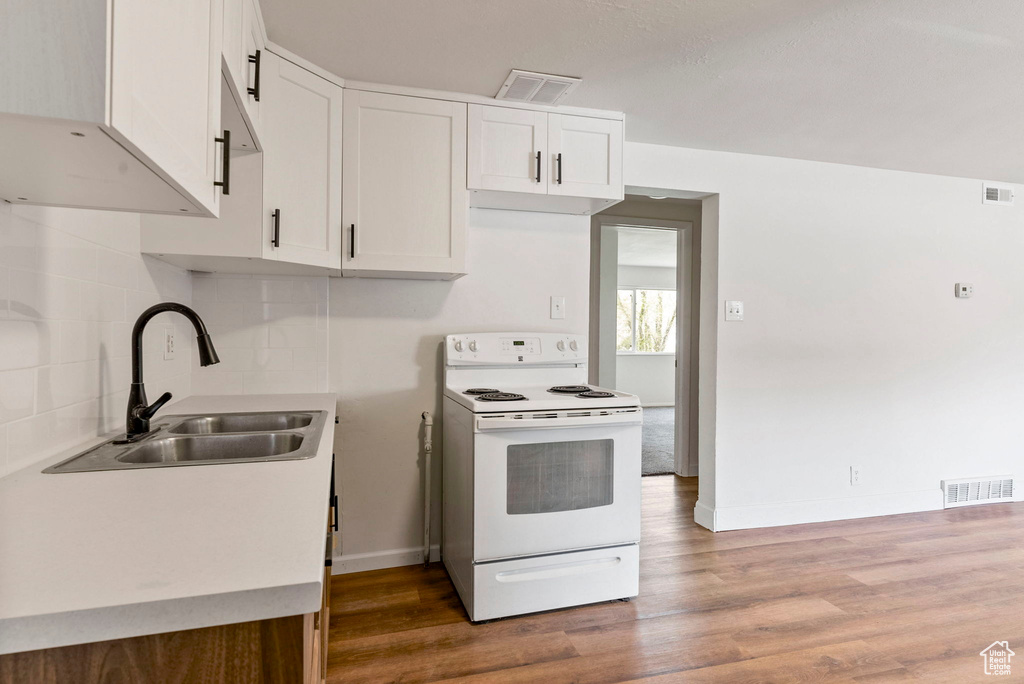 Kitchen with white cabinets, sink, tasteful backsplash, white electric range, and hardwood / wood-style flooring