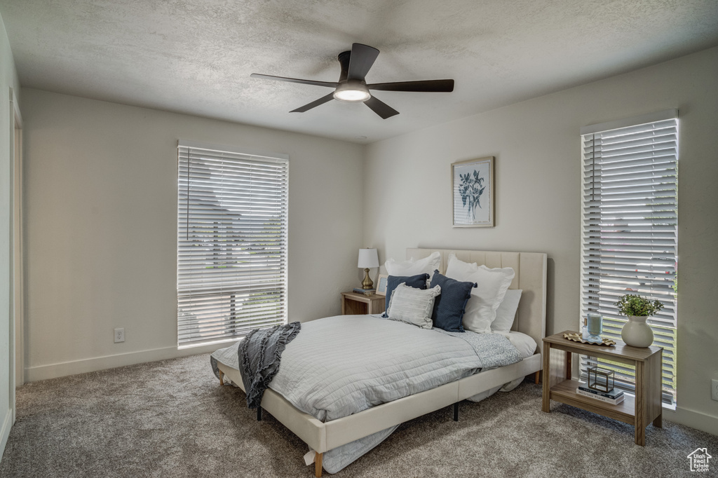 Bedroom featuring a textured ceiling, ceiling fan, and carpet floors