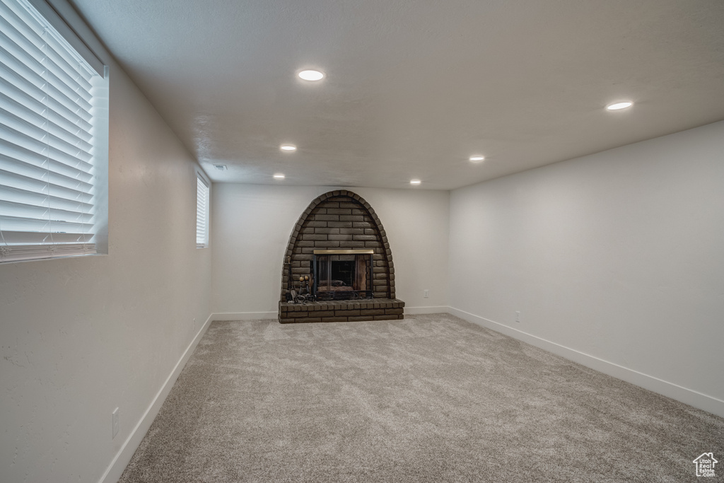Unfurnished living room with carpet floors and a brick fireplace