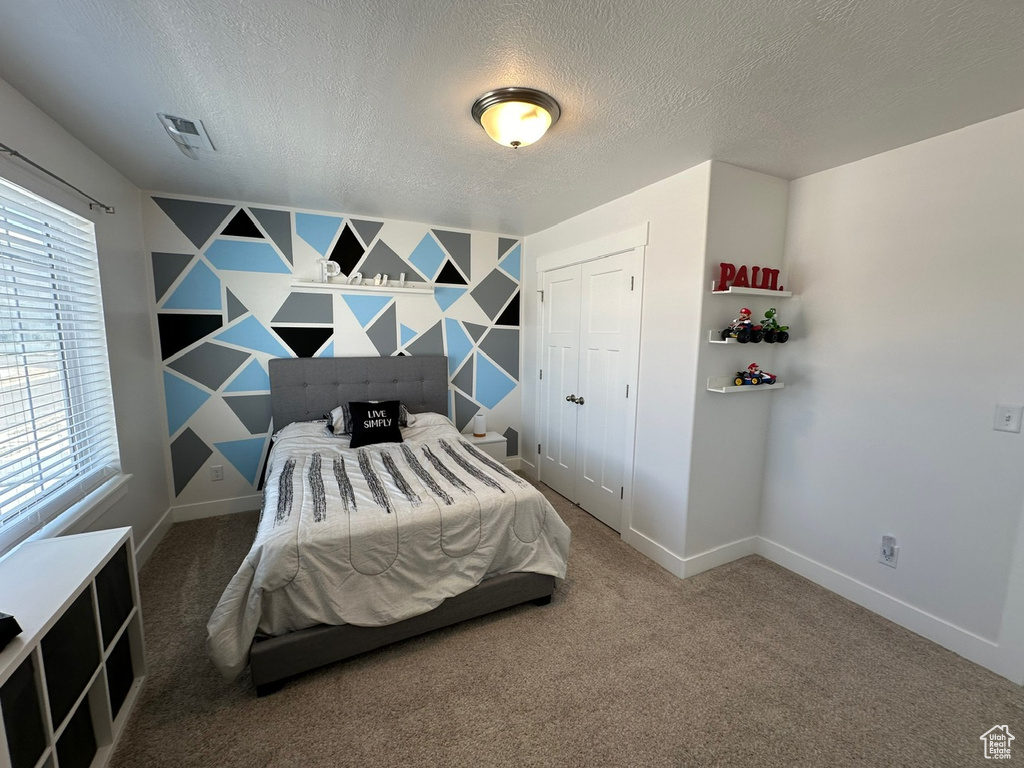 Bedroom featuring a closet, a textured ceiling, and carpet flooring