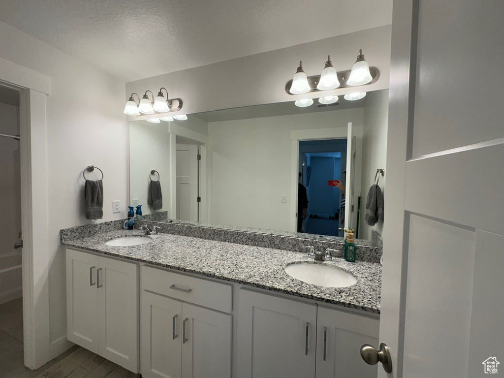 Bathroom featuring a textured ceiling and dual vanity