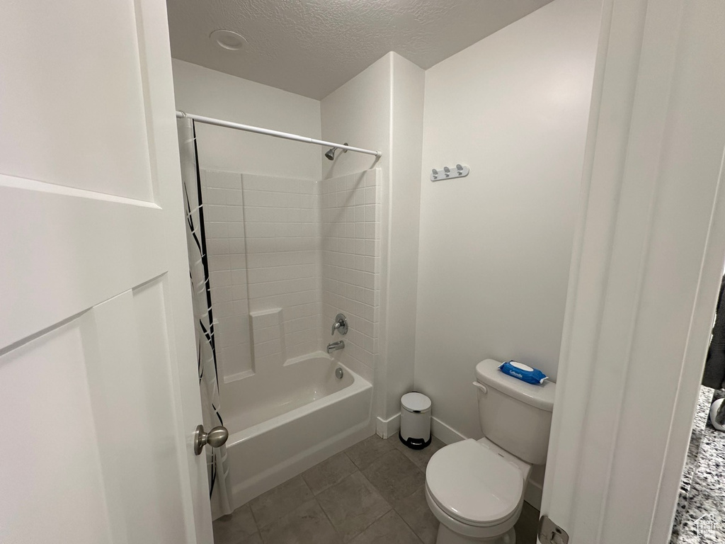 Bathroom with toilet, tile floors, a textured ceiling, and bathtub / shower combination