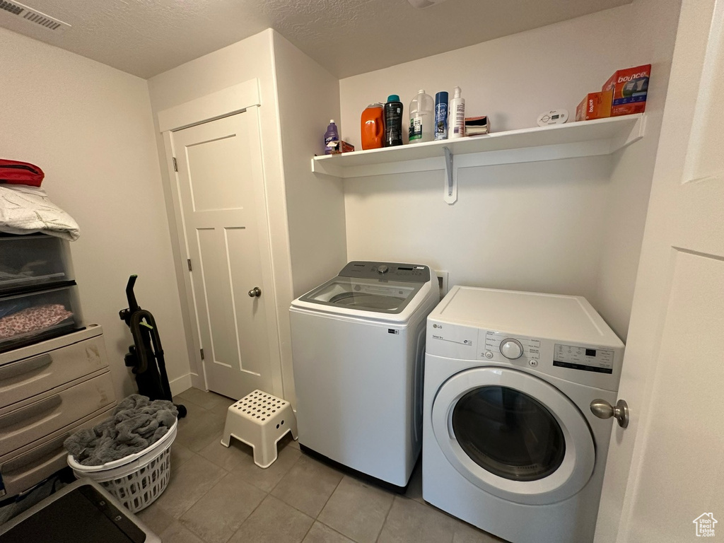 Washroom with tile flooring and washing machine and clothes dryer