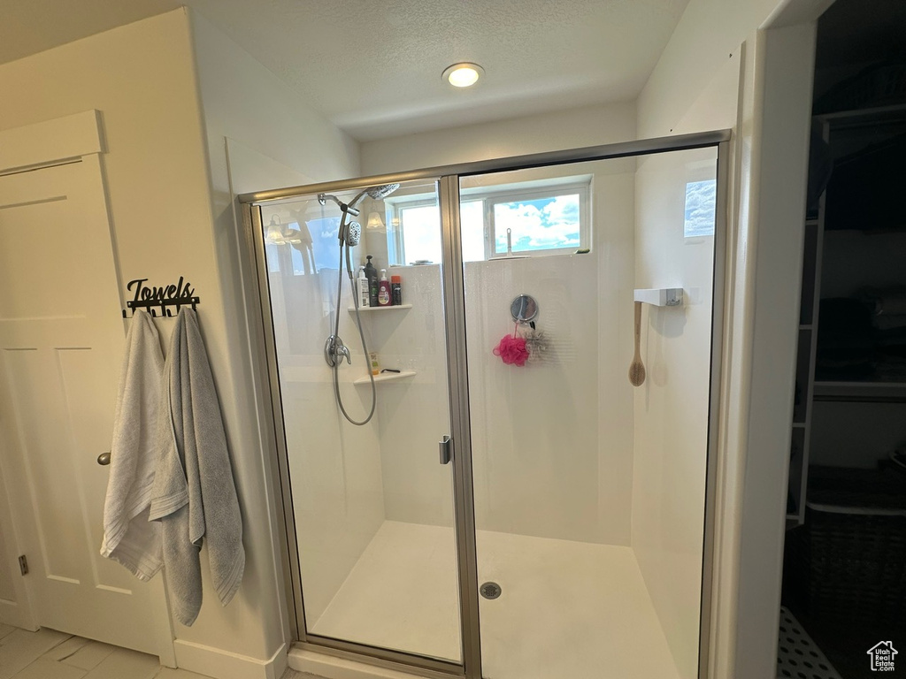 Bathroom with a shower with shower door, tile floors, and a textured ceiling