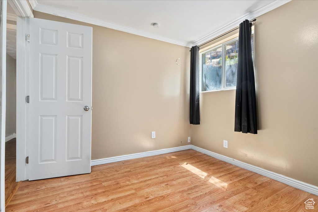 Spare room featuring ornamental molding and light wood-type flooring