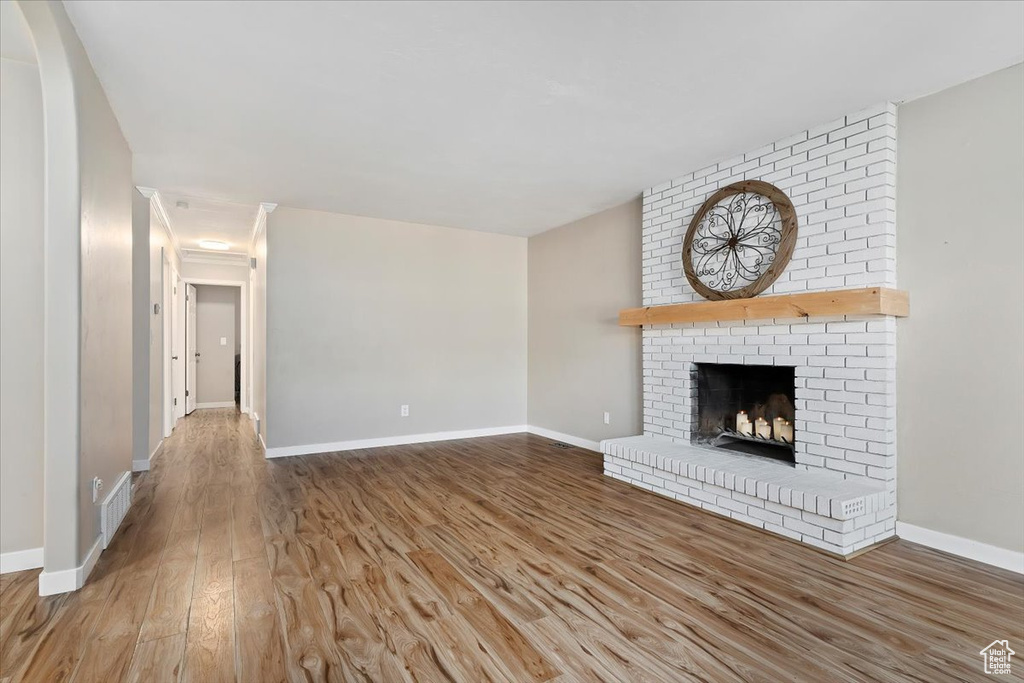 Unfurnished living room with hardwood / wood-style floors, brick wall, and a brick fireplace
