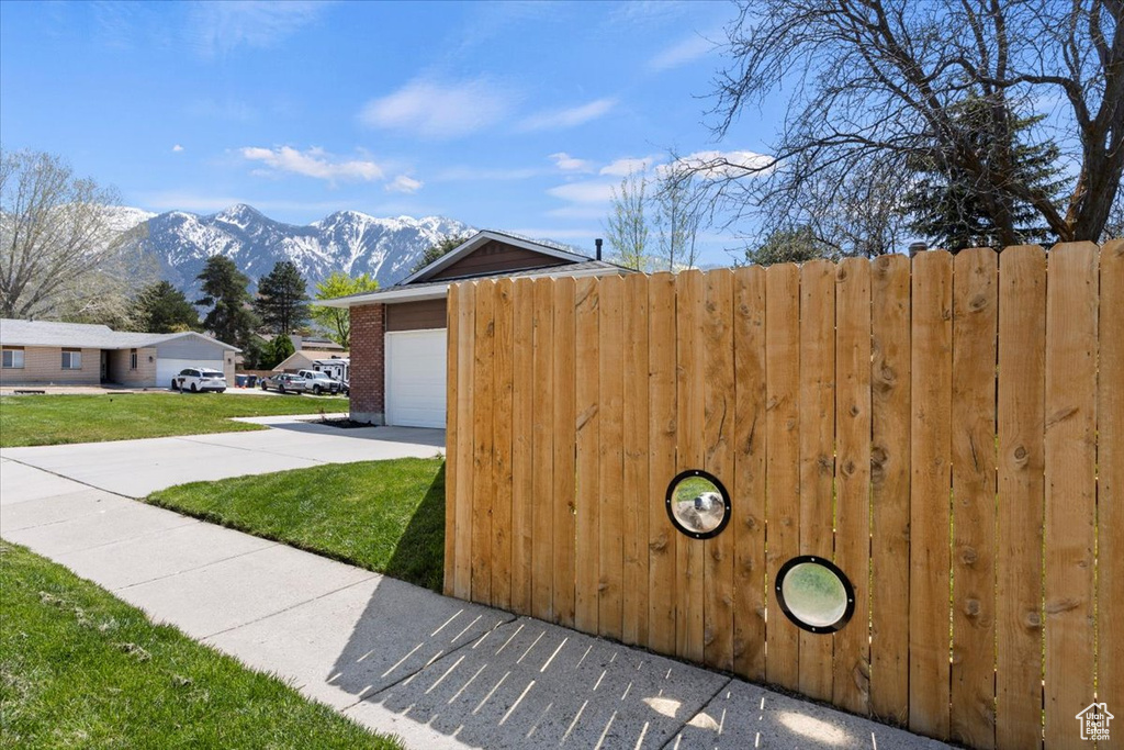 View of gate with a mountain view, a yard, and a garage