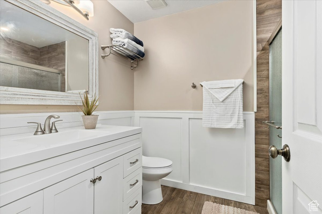 Bathroom featuring an enclosed shower, toilet, vanity, and hardwood / wood-style floors