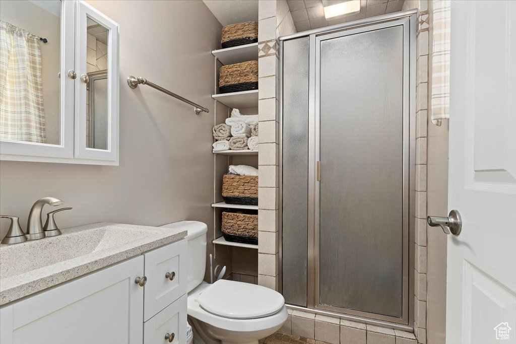 Bathroom with toilet, a shower with door, and large vanity