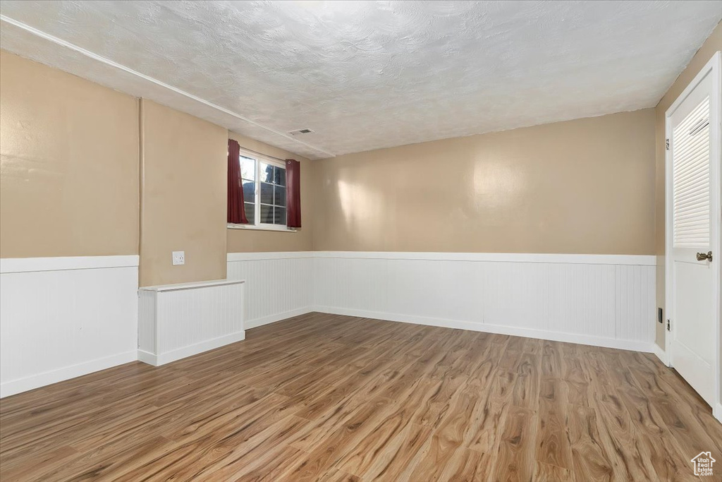Empty room featuring a healthy amount of sunlight, a textured ceiling, and hardwood / wood-style flooring