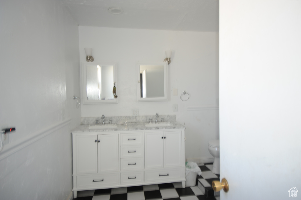 Bathroom with double sink vanity, toilet, and tile flooring
