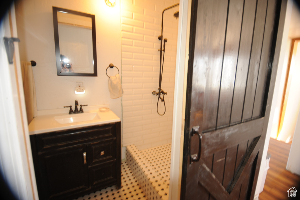 Bathroom featuring vanity, hardwood / wood-style floors, and a tile shower