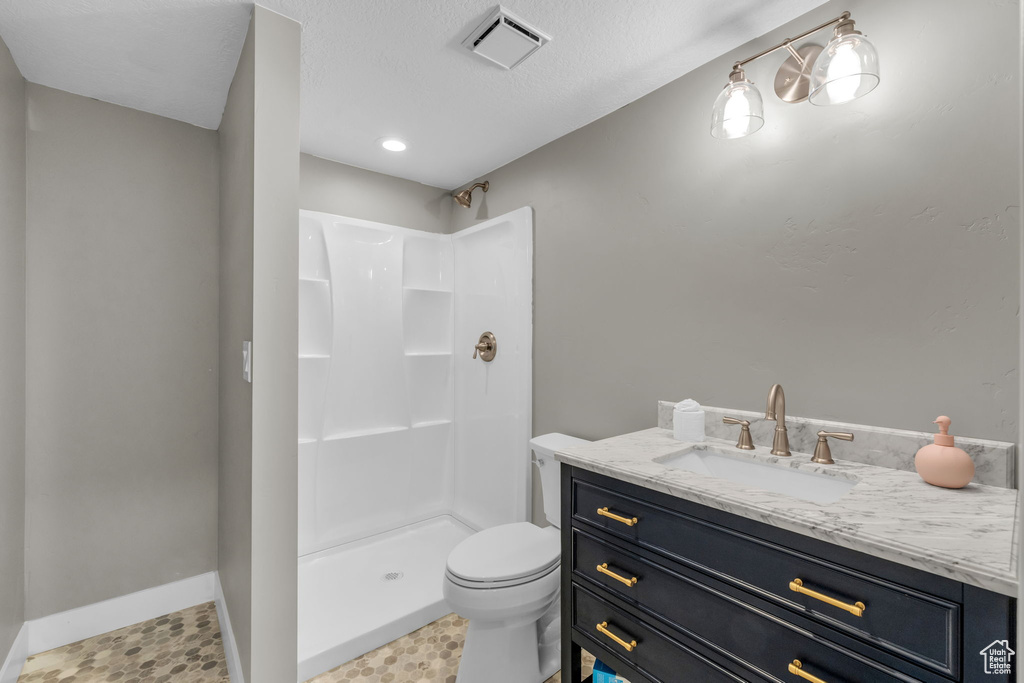 Bathroom featuring a textured ceiling, walk in shower, toilet, tile floors, and vanity