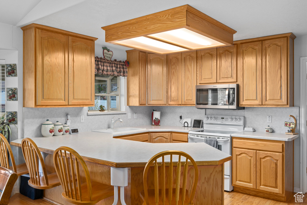 Kitchen featuring white electric stove, light hardwood / wood-style flooring, backsplash, kitchen peninsula, and sink