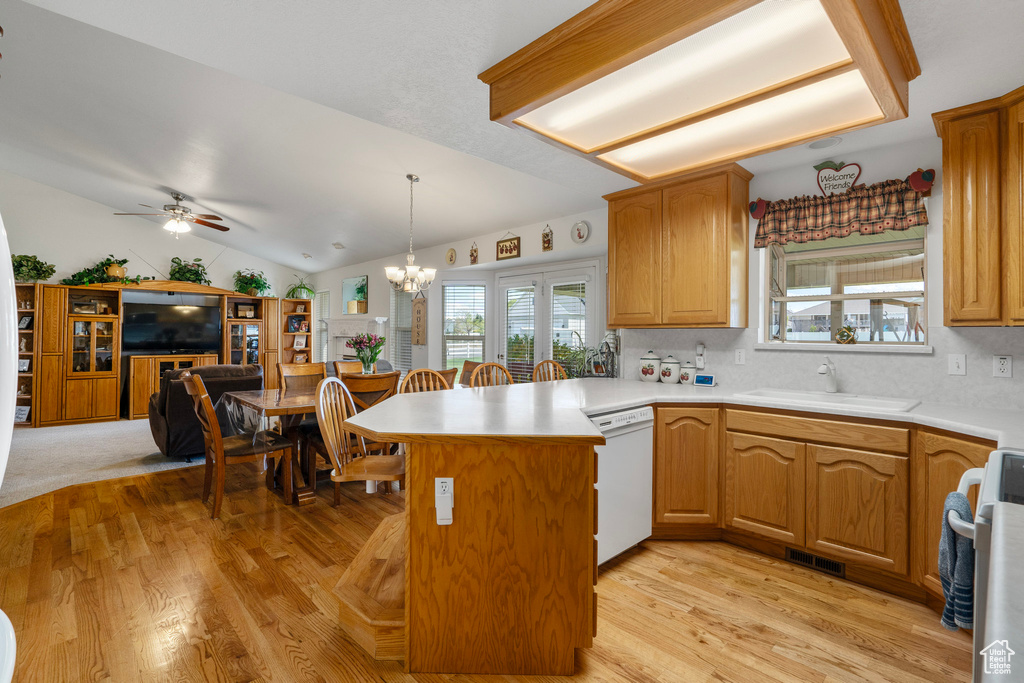 Kitchen with kitchen peninsula, decorative light fixtures, vaulted ceiling, dishwasher, and sink